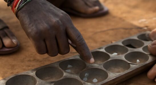 Mancala board with pits and stones arranged for sowing