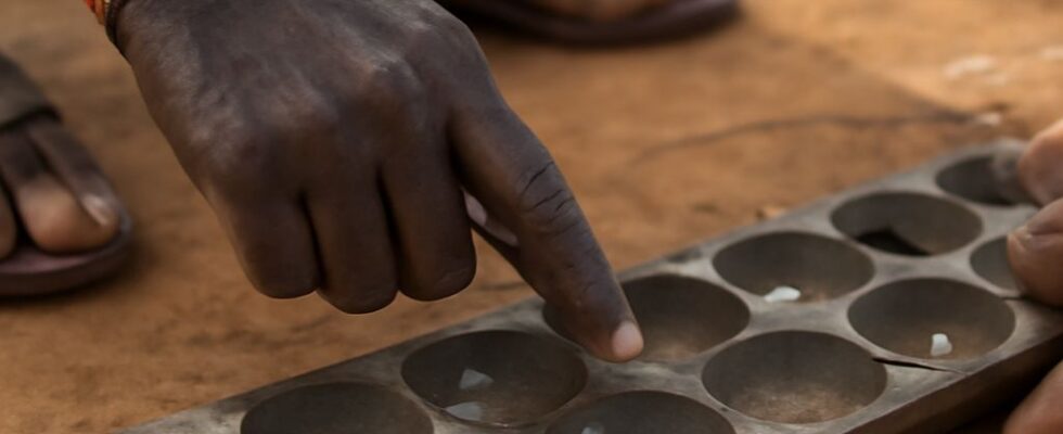 Mancala board with pits and stones arranged for sowing